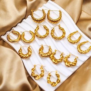 Polished gold plated stainless steel twist hoop earrings on elegant silk background