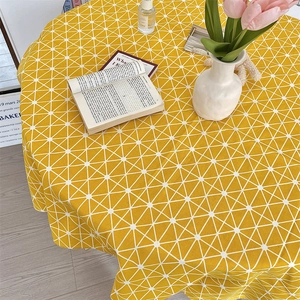 Macro detail of round yellow tablecloth with white geometric pattern and cotton linen texture