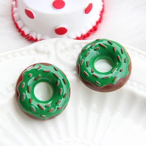 Detailed close-up of chocolate donut resin charms with green icing and red stripes