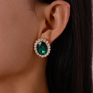 Close-up of vintage emerald green rhinestone oval stud earrings for women in gold