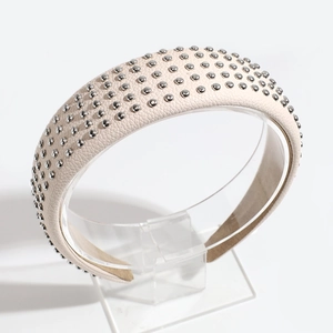 Detail view of beige lychee leather headband featuring studded silver rivets decoration