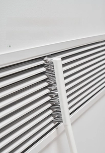 Detail view of a long nylon crevice brush cleaning narrow gaps of air conditioner vents