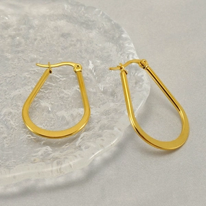 Polished gold U-shaped stainless steel earrings on textured glass with soft lighting