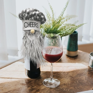 Detail of Christmas gnome wine bottle cover with CHEERS print on a festive dining table