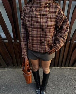 Close-up of brown plaid short jacket featuring large round buttons and stand collar style