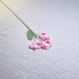 Detail view of handmade crochet puff flowers in pink gradient with green knitted leaves