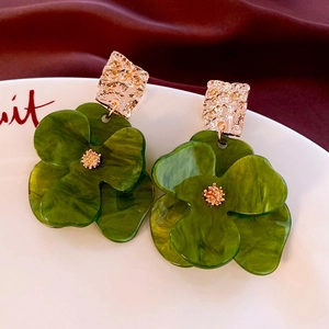 Macro view of green acrylic flower earrings with gold hammered metal and marble texture