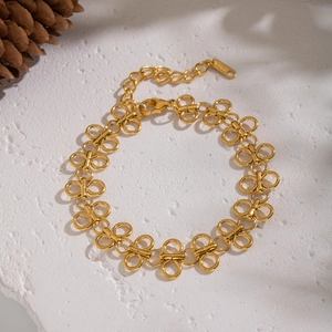 Detailed view of golden butterfly chain bracelet with lobster clasp on white stone surface