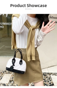 Detail of a black and white quilted shell crossbody bag with a gold chain strap