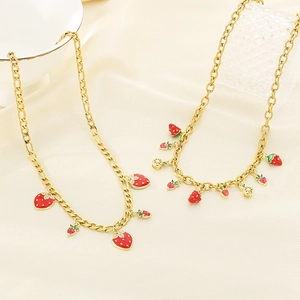 Détail de colliers dorés avec pendentifs fraises rouges 3D et citrons sur satin beige