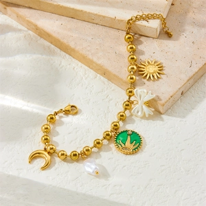Vintage gold plated bracelet with sun, moon, bow, and baroque pearl charms on stone surface