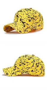 Detail view of cotton baseball cap with artistic black paint splatter on yellow fabric