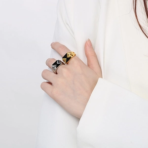Anelli geometrici color oro e argento con smalto nero indossati da una modella elegante