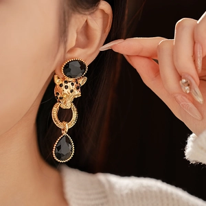 Close-up of vintage gold tiger head earrings with black stones on model's ear