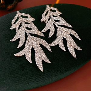 Detailed view of vintage silver leaf earrings with rhinestones on dark green velvet padding
