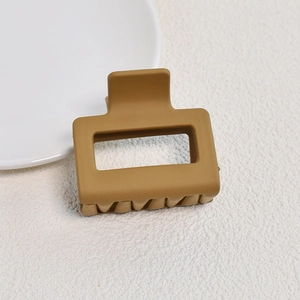 Detail view of small square ginger matte hair claw clip on white textured background