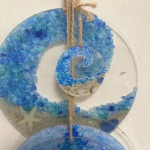 Close-up of Sea Glass Suncatcher with blue resin waves, real sand, and tiny seashells