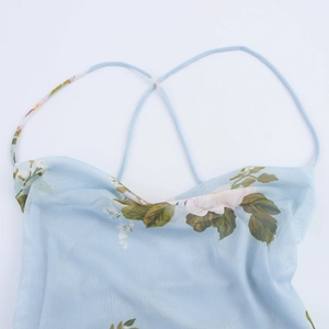 Détail de robe fleurie en mesh bleu clair avec fines bretelles et col bénitier élégant
