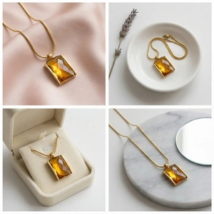 Macro shot of rectangular amber faceted crystal pendant on a gold snake chain necklace