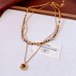 Détail du collier multicouche en perles d'œil de tigre plaqué or 18 carats sur tissu