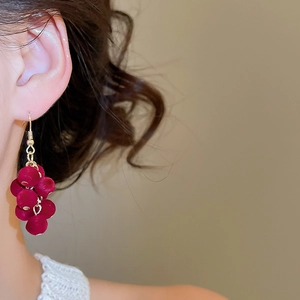 Close-up of gold hook earrings with red velvet pompom grape tassels on a model