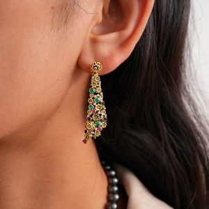 Macro shot of vintage gold flower earrings with colorful crystals and pearl necklace