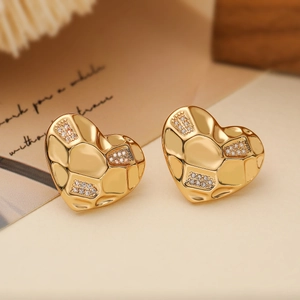 Macro detail of 18K gold plated heart stud earrings with quilted texture and zircon stones