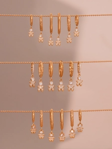 Detail of rose gold earrings with astronaut charms and zircon stones on ball chains
