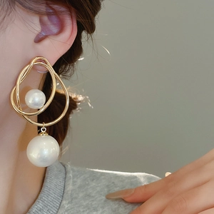 Gros plan d'un mannequin portant des boucles d'oreilles dorées avec perles blanches