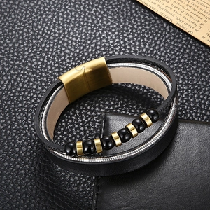 Macro detail of men's leather bracelet showing braided rope, beads and gold magnetic clasp