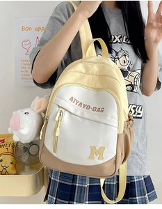 Detail of color-block school backpack in yellow and khaki with cute bunny charm accessory