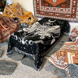 Bohemian moth and moon phase woven throw blanket with fringe displayed on a table