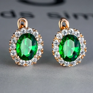 Detailed close-up of emerald green oval stud earrings with pavé white zircon halo