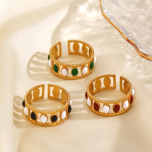 Three gold stainless steel enamel rings with colorful oval beads on beige silk fabric