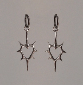 Close-up of silver thorn heart earrings with hollow gothic design and polished hoops