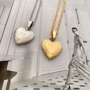 Detail of vintage heart-shaped locket necklaces with engraved floral patterns in gold and silver