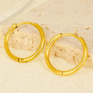 Detailed macro view of polished gold stainless steel hoop earrings on stone background