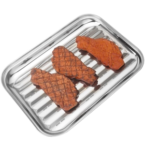 Square stainless steel grill pan with grease drainage holes and seared steaks on top
