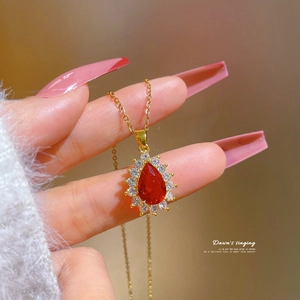 Macro detail of luxury water-drop red ruby pendant with micro-pave crystals in gold finish