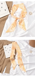 Detail of orange tropical palm print skinny silk scarf with letter E accent for women