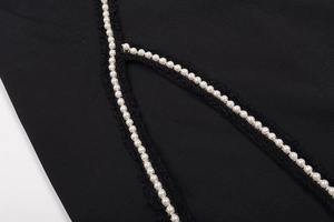 Detail of black woven lace with white pearls on a sexy cutout evening dress
