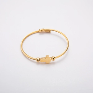 Close-up of gold stainless steel cable bracelet featuring cross charm and bead accents
