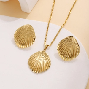 Detailed view of golden shell necklace and earrings set with fine texture on white stand