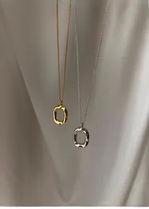 Close-up of irregular oval pendant necklaces with textured gold and silver finishes