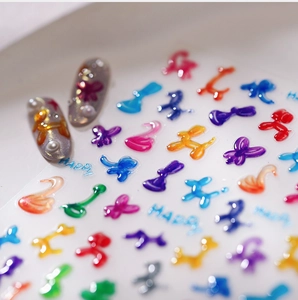 Macro detail of 3D jelly butterfly and balloon dog nail stickers on grey base