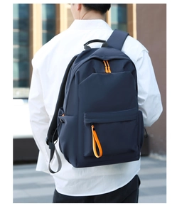 Detail showing dark blue waterproof backpack with contrasting orange zipper and nylon fabric