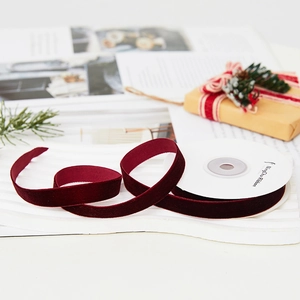 Luxurious dark red velvet ribbon on white textured base for elegant gift wrapping