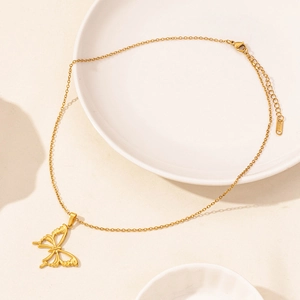Elegant gold butterfly pendant necklace with fine chain displayed on a ceramic plate