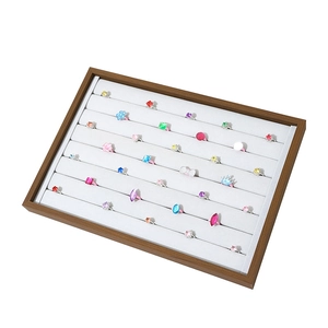 Walnut wood jewelry display tray with grey velvet slots holding various decorative rings