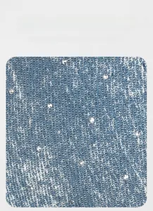 Macro shot of rhinestone-embellished denim fabric with vintage wash texture